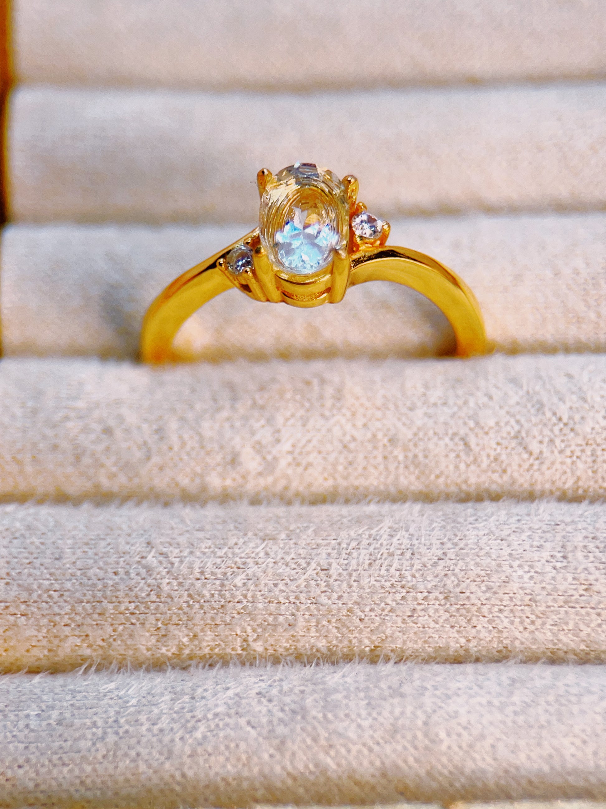 Gold ring with a blue gemstone on a beige fabric background