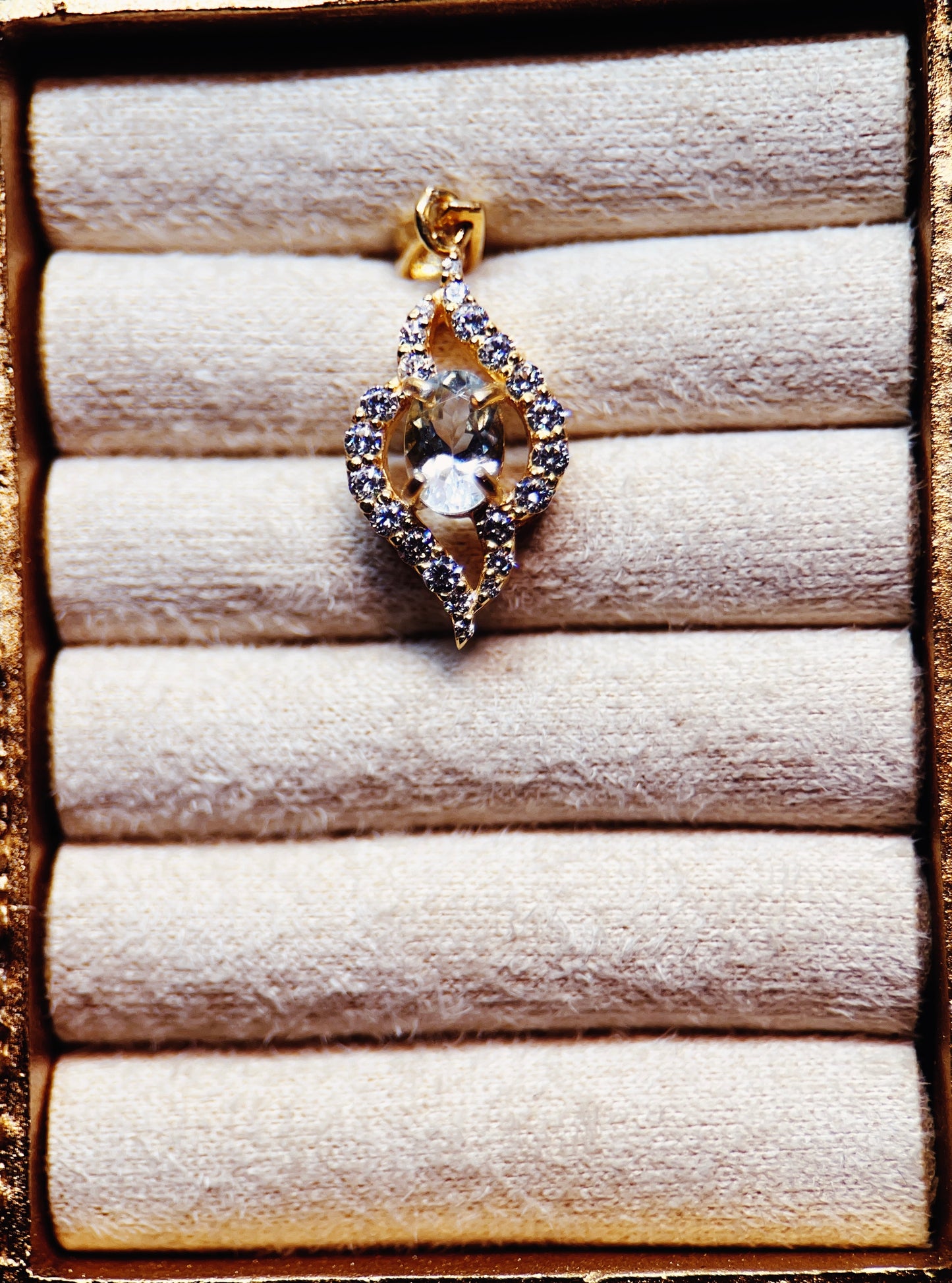 Gold pendant with a central gemstone on a textured surface