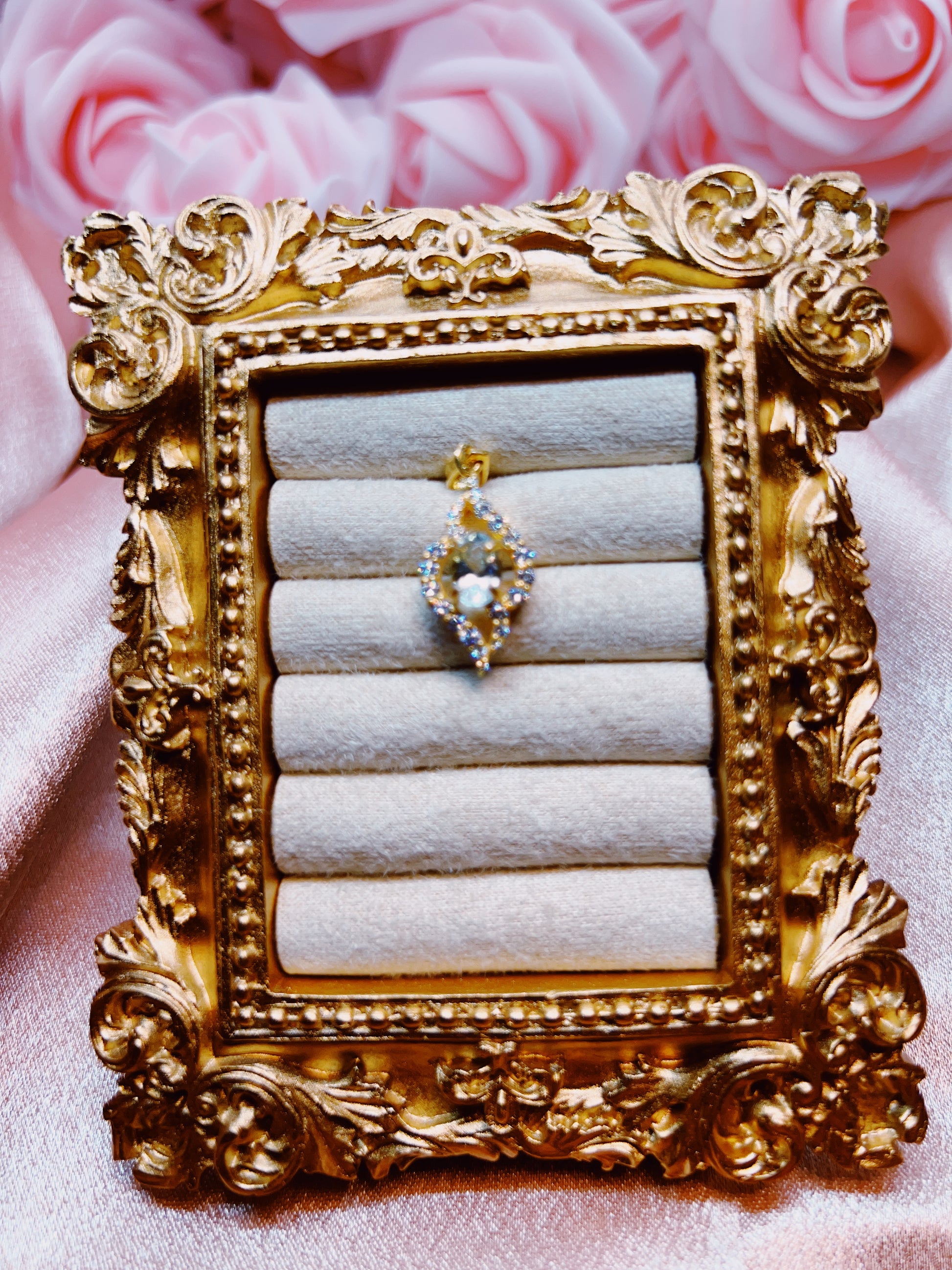 Decorative gold jewelry holder with a ring and earring on a pink floral background