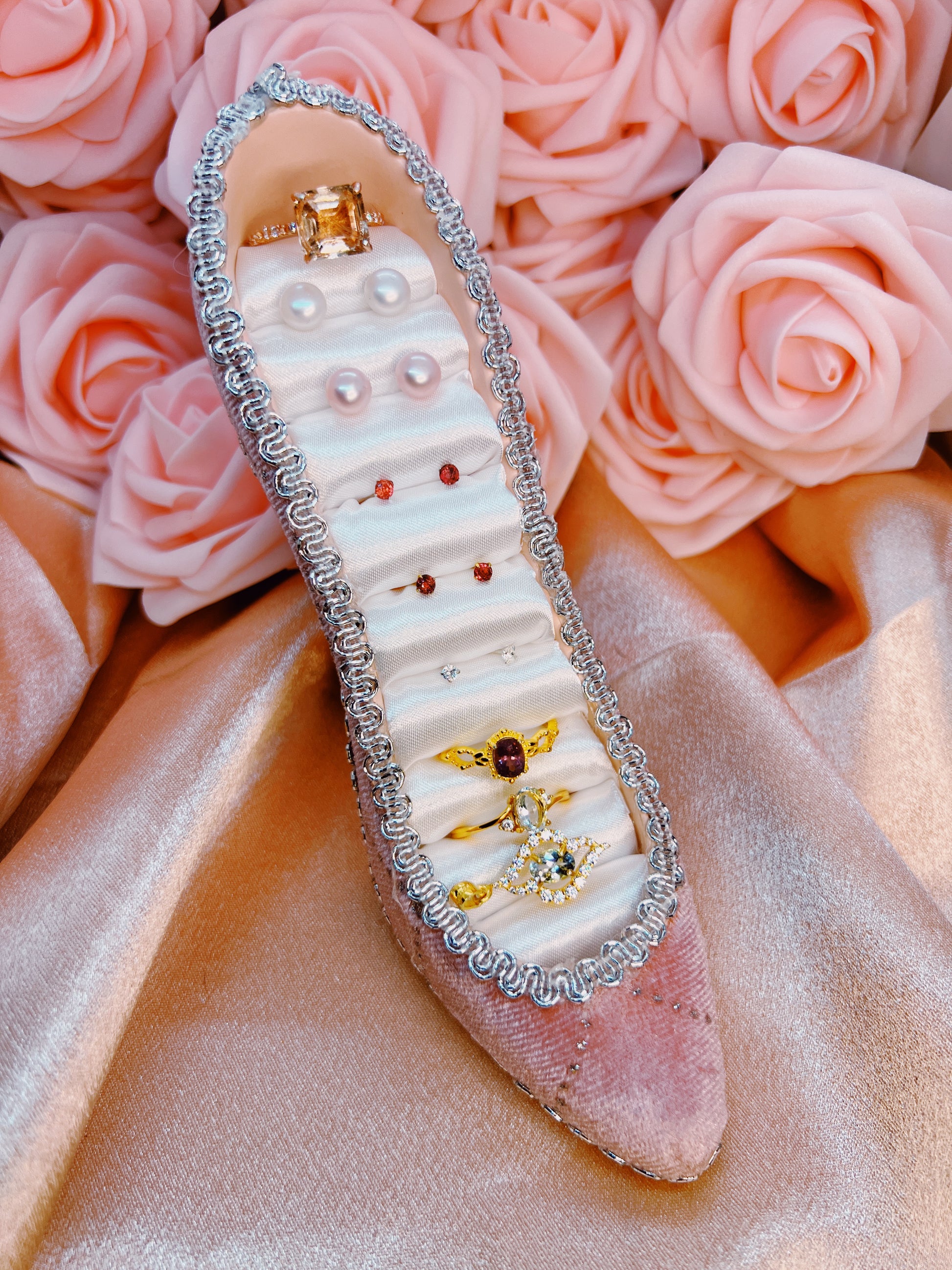 Decorative shoe with embellishments on a bed of pink roses
