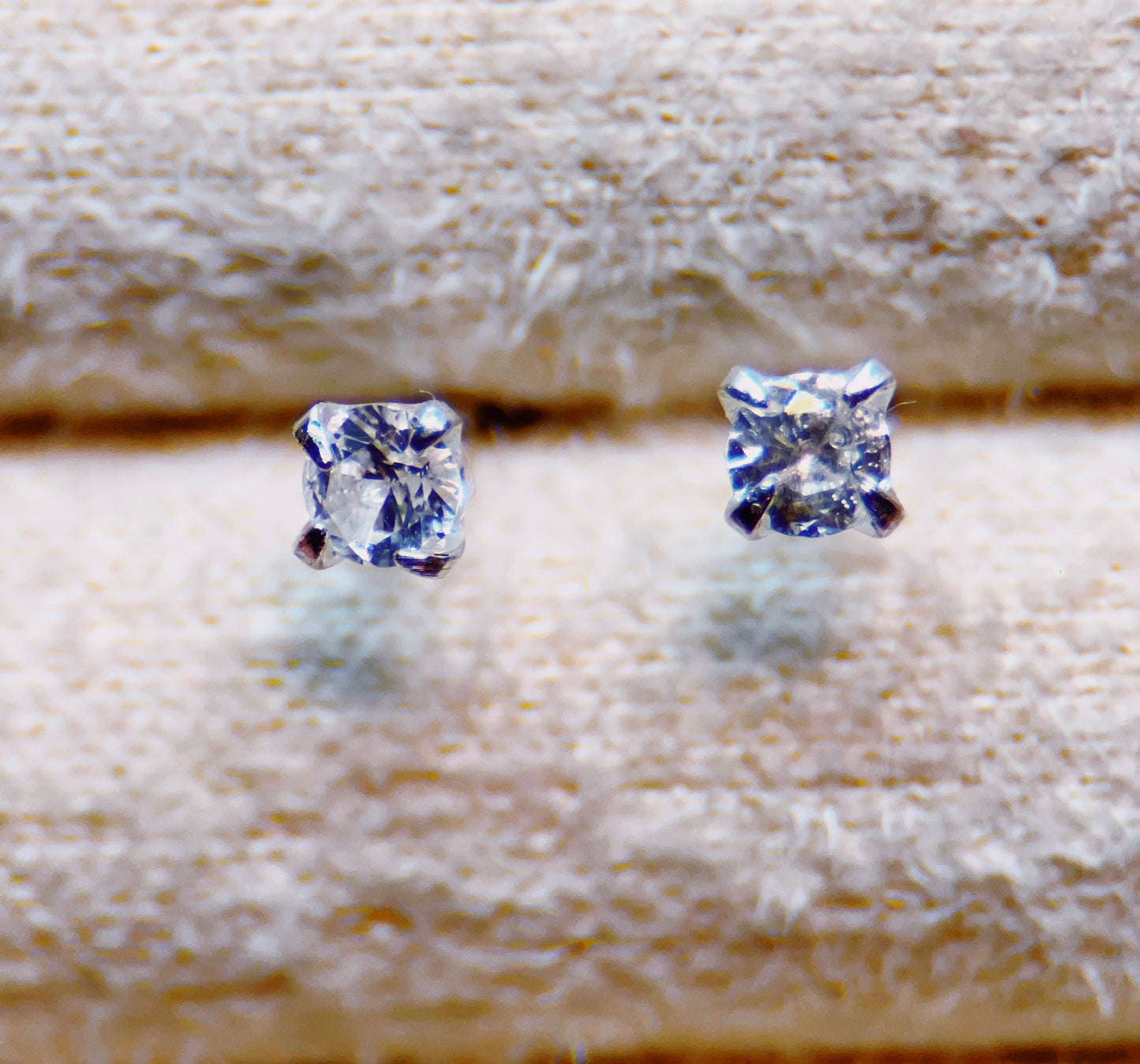Topaz stud earrings on a textured beige background