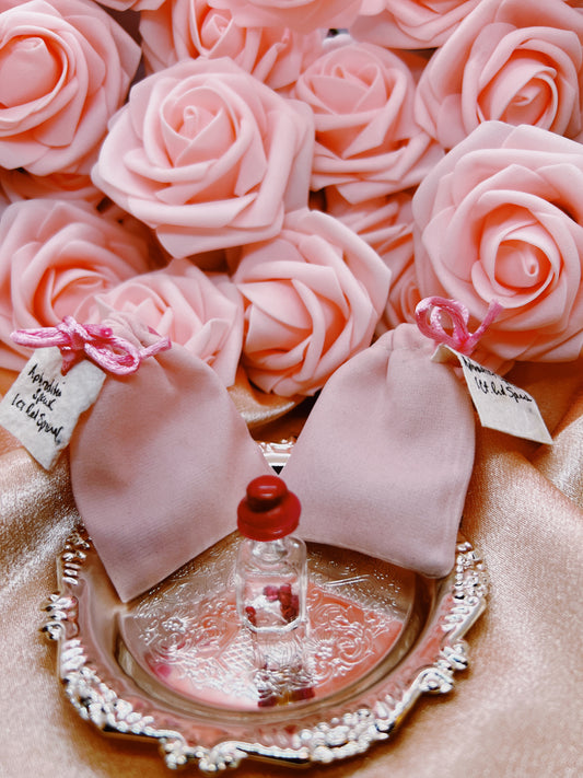 Pink rose-shaped candies with small bottles on a decorative plate.