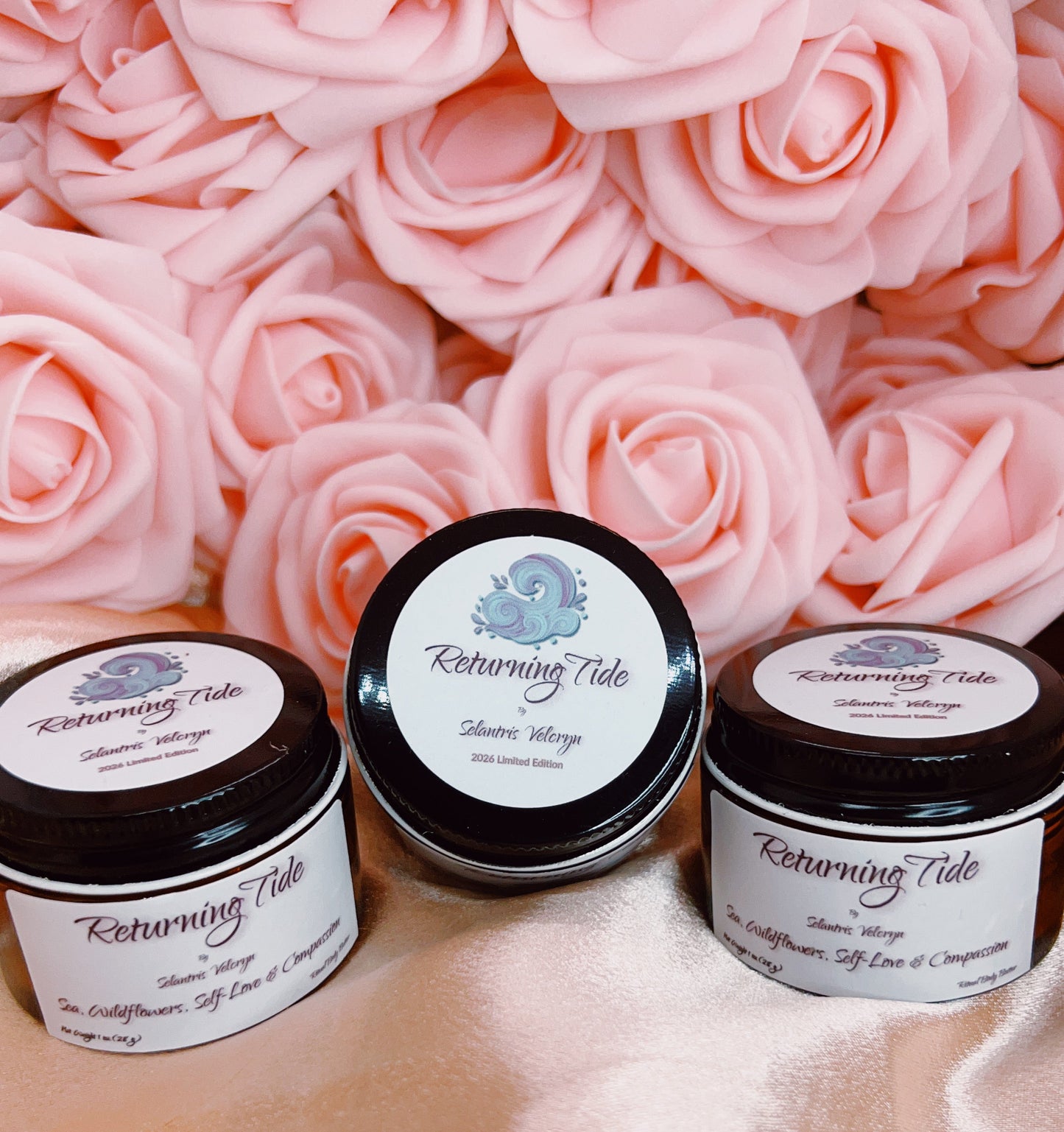 Three jars of 'Returning Tide' body butter on a pink surface with pink roses in the background