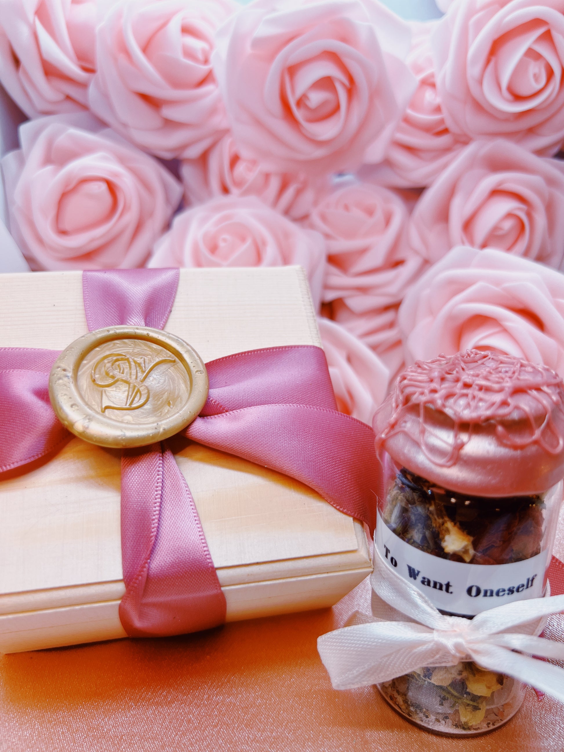 Gift box with pink ribbon and seal, surrounded by pink roses