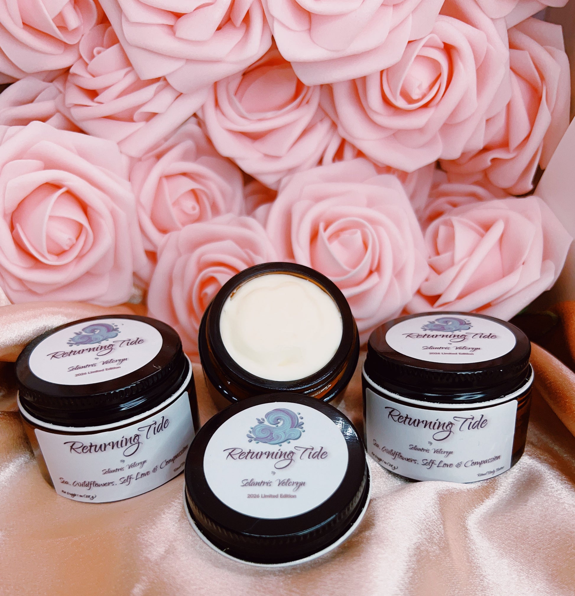 Four jars of cream with labels on a pink floral background