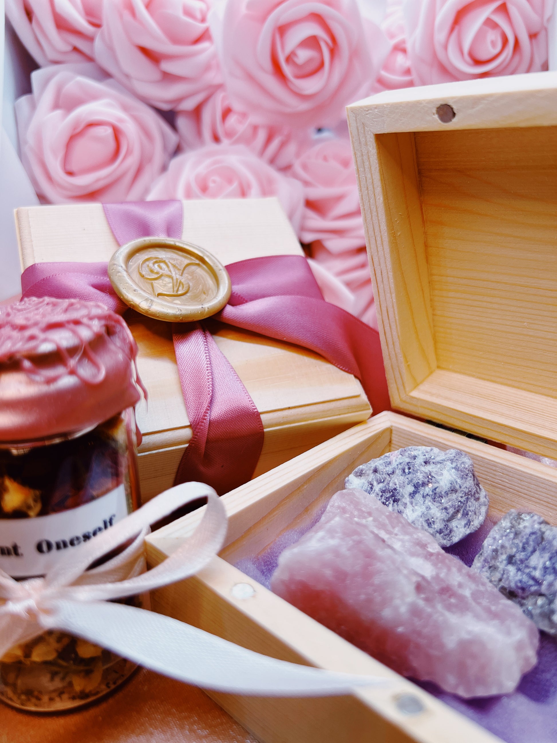 Wooden box with crystals, bottle labeled 'Just Oneself', and pink roses in the background